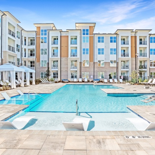 Resort-Inspired Swimming Pool resort-inspired swimming pool surrounded by white lounge chairs and private cabanas at Bainbridge Cary Apartments in NC